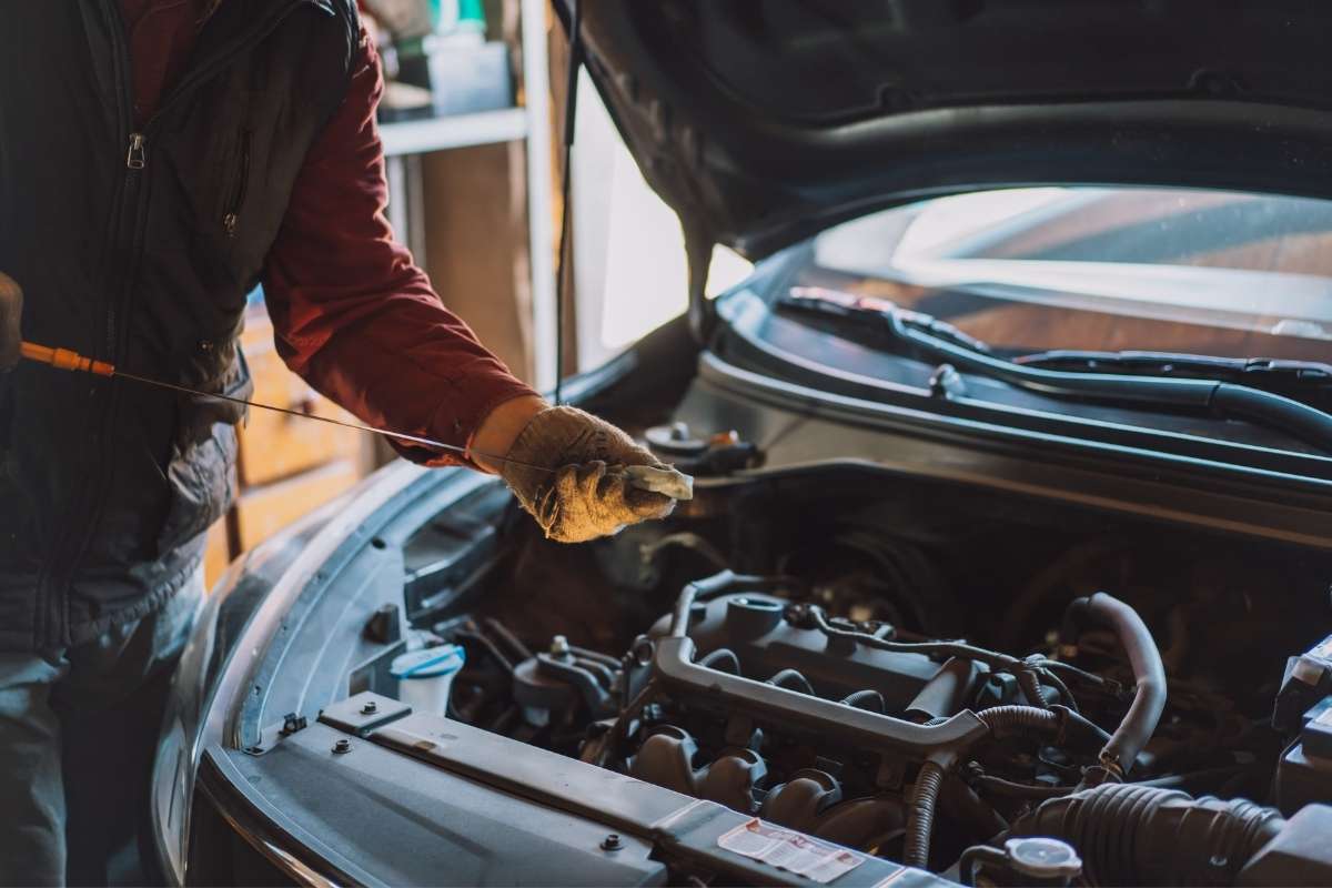 osoba proverava ulje u automobilu